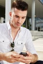 Serious man looking at mobile phone sitting outside in city Royalty Free Stock Photo