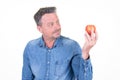 Serious man looks longingly at a red apple in his hand  isolated over white background Royalty Free Stock Photo