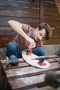 Serious man screwing skateboard truck to deck