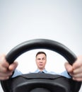 Serious man in a shirt and tie turns the steering wheel with his hands, front view on light background. Driver car concept Royalty Free Stock Photo