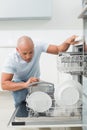 Serious man using dish washer in kitchen Royalty Free Stock Photo