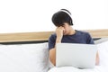 Serious man using Laptop and Head Phone while sitting on Bed