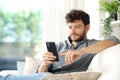 Serious man using phone on a couch at home Royalty Free Stock Photo