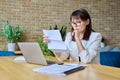 Serious mature businesswoman reading official letter, sitting in office