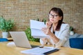 Serious mature businesswoman reading official letter, sitting in office