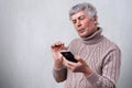 A serious mature man holding smartphone in his hand looking attentively into the screen. Senior man reading text message on phone Royalty Free Stock Photo