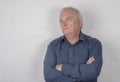 Serious mature man thinking, standing against a white brick background Royalty Free Stock Photo