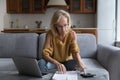 Serious older woman calculates household finances, paying bills on laptop