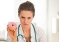 Serious medical doctor woman showing donut