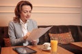 Mid-adult business woman sitting in a cafe reading reports Royalty Free Stock Photo