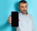 Serious Middle Aged Man Showing Phone Blank Screen, Blue Background Royalty Free Stock Photo