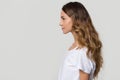 Serious millennial woman standing in profile on white grey background