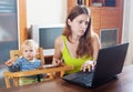 Serious mother with baby using laptop