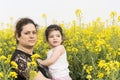 Serious mother embraced her little girl at canola field-family having fun together on canola farm