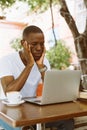 Serious multiracial businessman using laptop in cafe with head in hands in cafe. Video call and read finance information Royalty Free Stock Photo