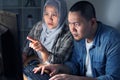 Serious muslim Asian man and woman working at night on computer. Focused professional male and female business people using laptop Royalty Free Stock Photo