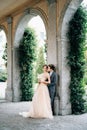 Serious newlyweds are hugging leaning against the arch against the backdrop of greenery. Lake Como