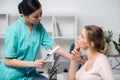 Serious nurse holding clipboard with diagnosis and talking with pensive young patient