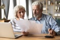 Serious older couple reading financial documents, planning budget