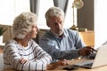 Serious older couple using laptop, planning budget, checking bills