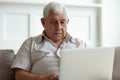 Serious older man using laptop close up, looking at screen