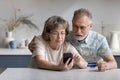 Serious older married couple shopping on internet stores