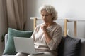 Serious older woman using laptop for video call from home