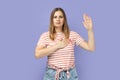 Serious patriotic woman raising one arm and putting on chest another making oath, swearing.