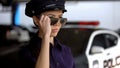 Serious patrolwoman in police uniform putting on sunglasses, ready for duty