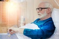 Serious pensioner taking a pill from a pillbox while staying in bed Royalty Free Stock Photo