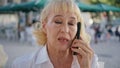 Serious pensioner talking mobile phone on street close up. Worried lady calling Royalty Free Stock Photo