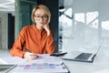 Serious and pensive business woman behind paper work inside office, female financier worker thinks about contracts and