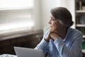 Serious pensive older businesswoman distracted from work staring out window