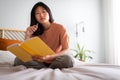 Serious, pensive teen asian female college student sitting on bed writing on diary looking at camera. Copy space. Royalty Free Stock Photo