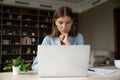 Serious pensive young employee working at laptop from home