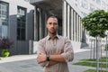 Serious and pensive young office worker with crossed arms looking at camera, businessman in shirt outside office Royalty Free Stock Photo