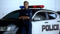 Serious policewoman in uniform leaning on patrol car, maintenance of order Royalty Free Stock Photo