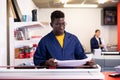 Serious print shop worker cuts paper on professional cutter