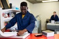 Serious print shop worker cuts paper on professional cutter