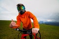 Serious professional cyclist in sportswear and helmet standing with a downhill bike on top of a hill, showing thumbs up Royalty Free Stock Photo