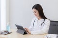Serious professional doctor wearing white coat and stethoscope holding modern touchscreen gadget using digital tablet computer at Royalty Free Stock Photo