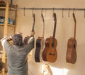Serious professional guitar-maker takes with unfinished guitar at workshop