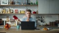 Serious programmer working remotely at kitchen. Woman dancing near busy husband.
