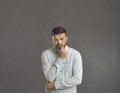 Serious puzzled sad man thinking looking down keeping fist at chin studio shot