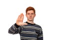 Serious redhead young boy teenager with a hand gesture shows Stop drugs or wars or pollution, isolsted