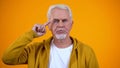 Serious retired male showing screw loose sign on camera, nonsense or absurd Royalty Free Stock Photo