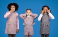 Serious, sad international little girls in casual close mouth, ears, eyes with hands isolated on blue background Royalty Free Stock Photo