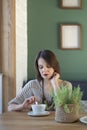 Serious sad irritated woman in cafe with cup of latte coffee. Middle-aged woman sits at a table in cafe. Vertical frame Royalty Free Stock Photo