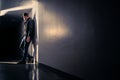 Serious sad man standing in dark corridor. Mystery guy in spotlight. Dramatic light and shadow. Stalker or outcast.