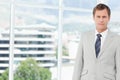 Mid adult man wearing suit jacket with striped tie standing in office by windows, copy space Royalty Free Stock Photo